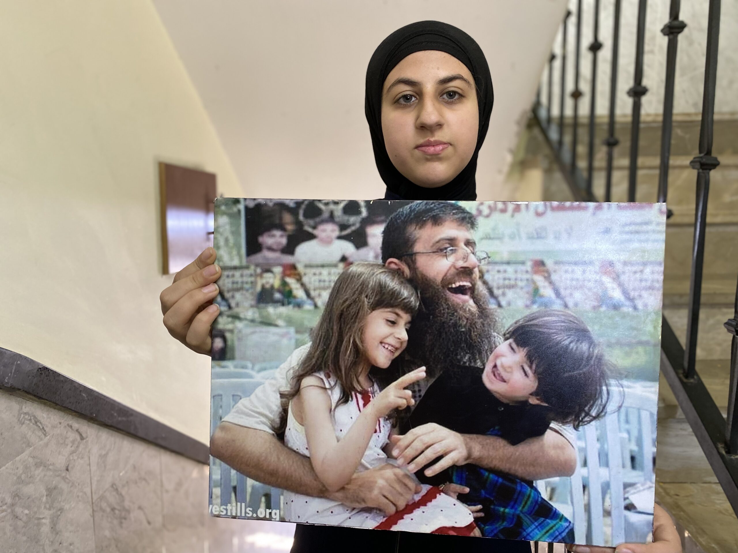 معالي، ابنه الشهيد خضر عدنان، تحمل صورةً قديمة برفقة والدها. (عدسة: شذى حماد).